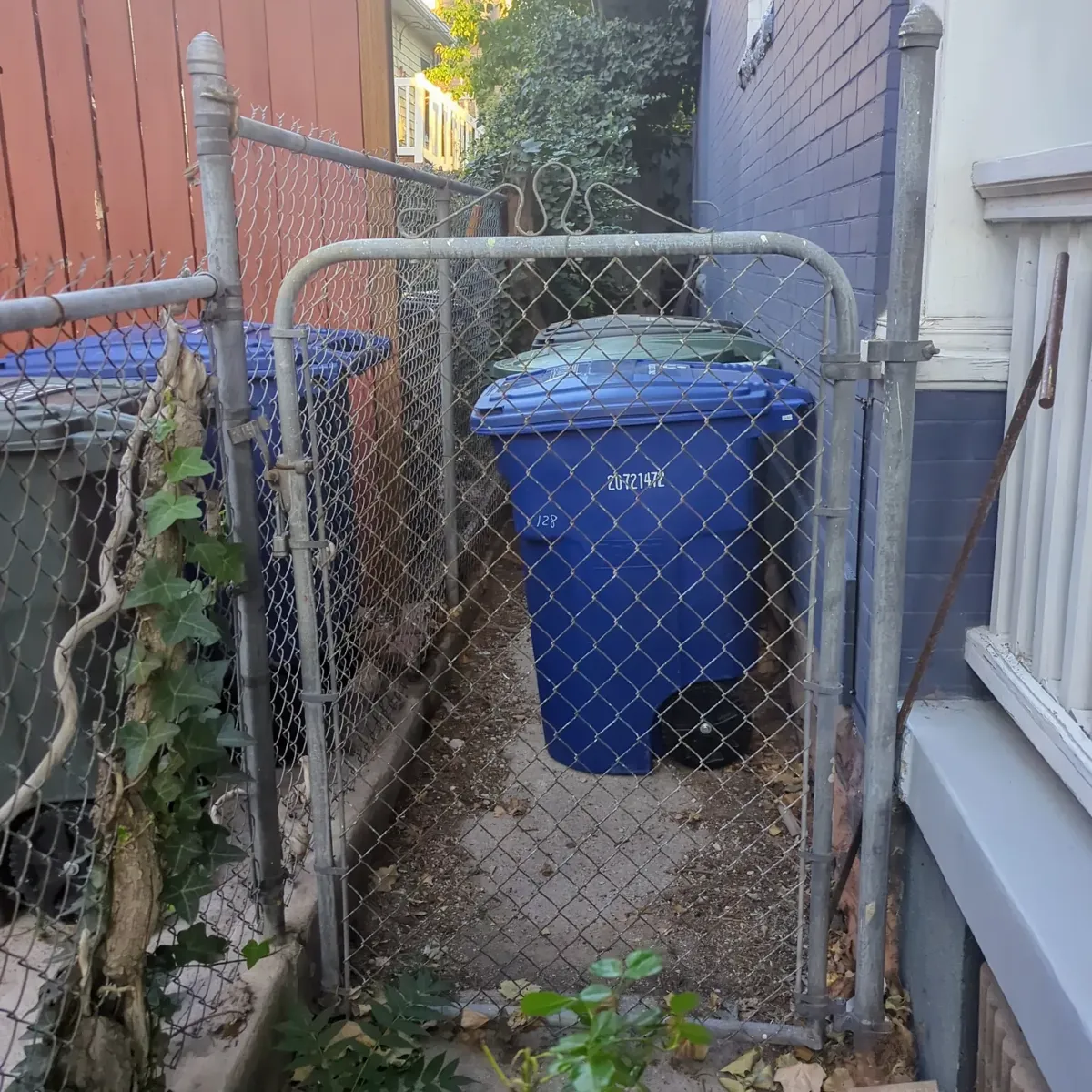 Old chain-link side gate, rusted hinges, no privacy